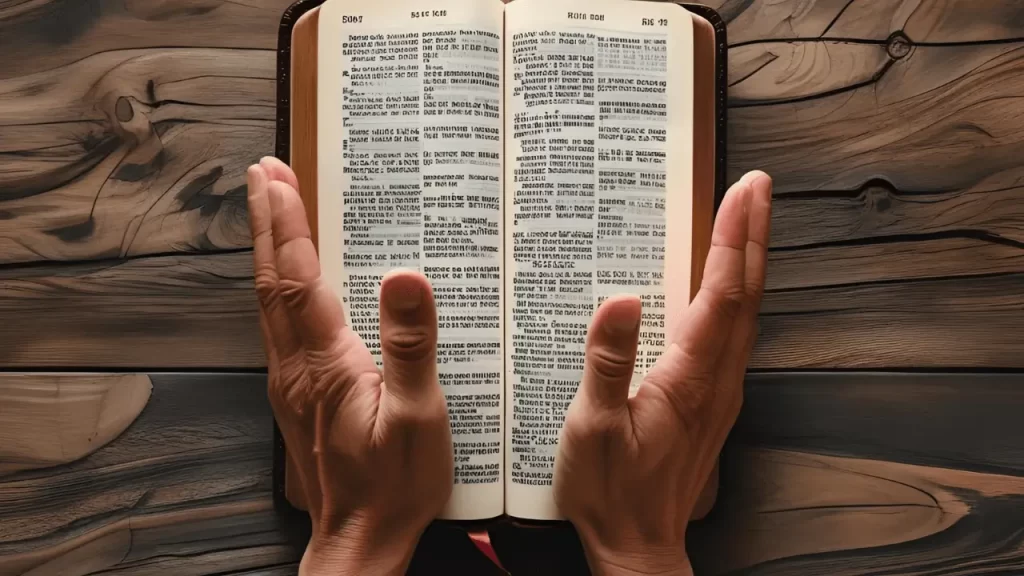 Mãos abertas em oração sobre uma Bíblia. Ilustrando o momento de reflexão e aplicação da Palavra.