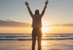 Imagem do devocional – Mulher em pé com braços levantados ao céu durante o nascer do sol, expressando louvor e alegria.