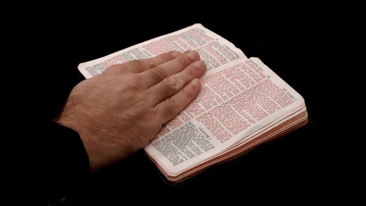 Mão sobre a Bíblia, representando a Palavra de Deus trazendo paz interior para o Devocional de hoje