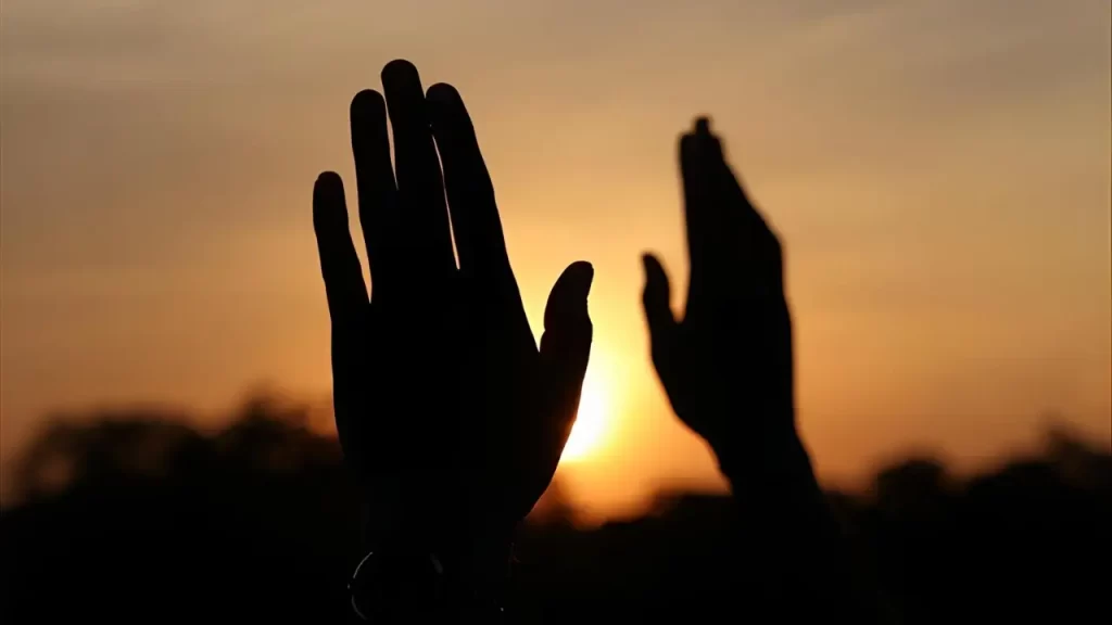 Mãos erguidas em oração ao pôr do sol, refletindo confiança nas promessas de Deus – Devocional de Hoje.