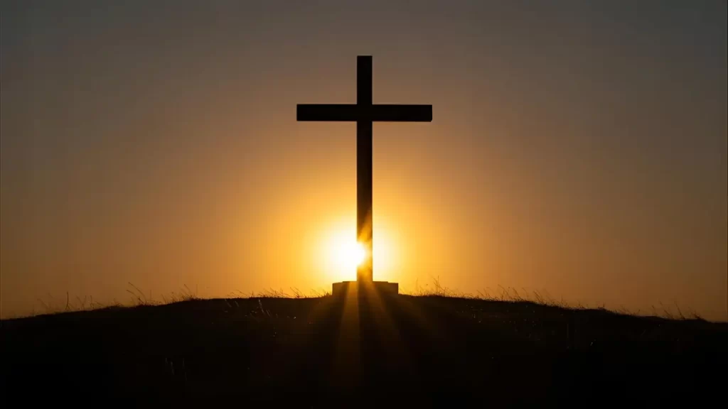 Cruz iluminada ao amanhecer representando a esperança e cumprimento das promessas bíblicas.