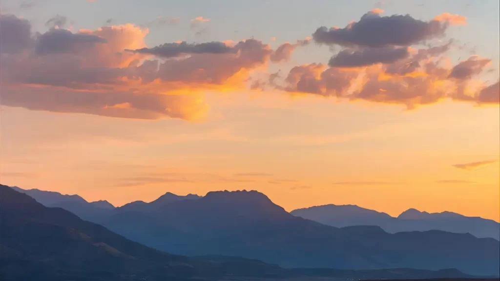 Uma paisagem serena de  montanhas, céu ao amanhecer com pôr do sol transmitindo paz e esperança. 