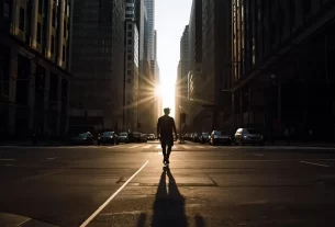 Uma pessoa caminhando sozinha em meio à cidade moderna. Representa a busca pela santidade na vida cristã em meio à correria e tentações do mundo atual.