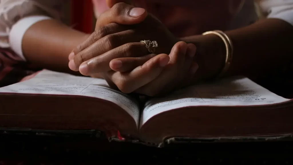 Pessoa em oração diante de uma Bíblia aberta.
