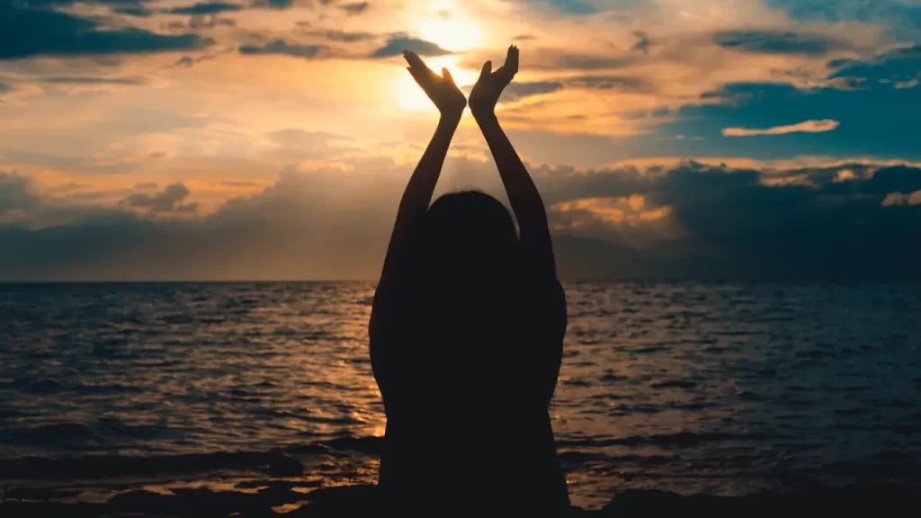 Pessoa em oração, mãos erguidas.